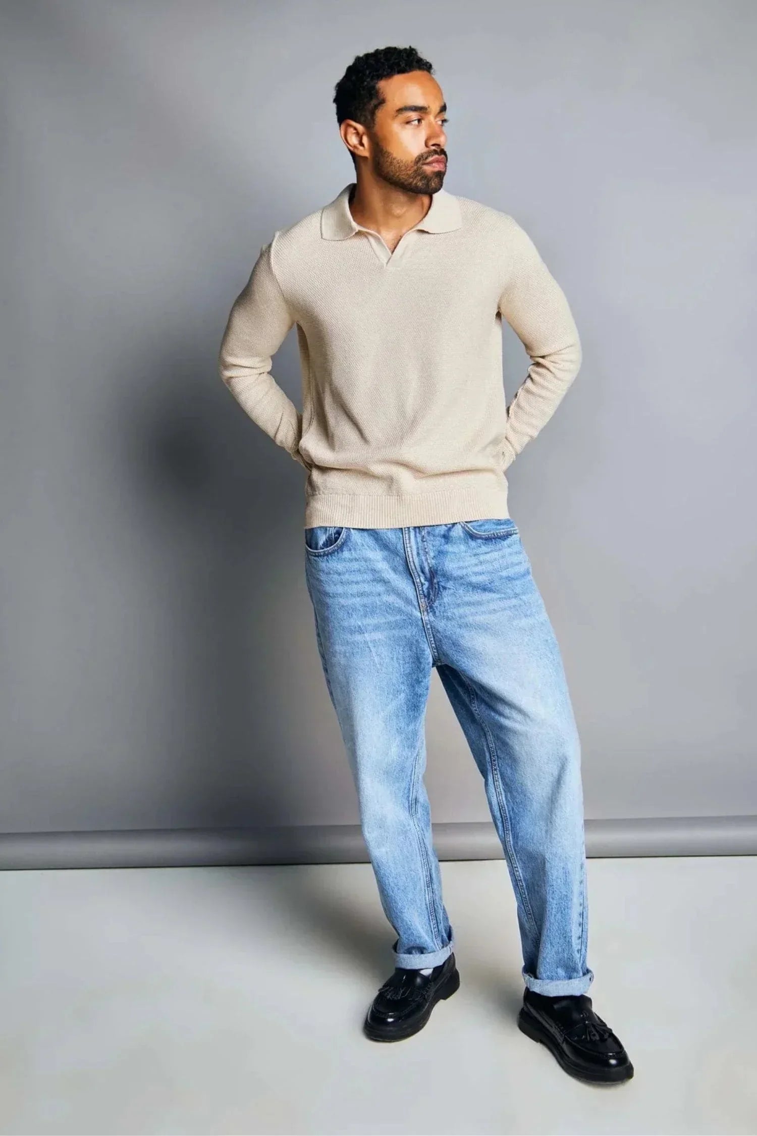 Hombre con suéter beige de punto para hombre y jeans holgados, moda casual masculina.